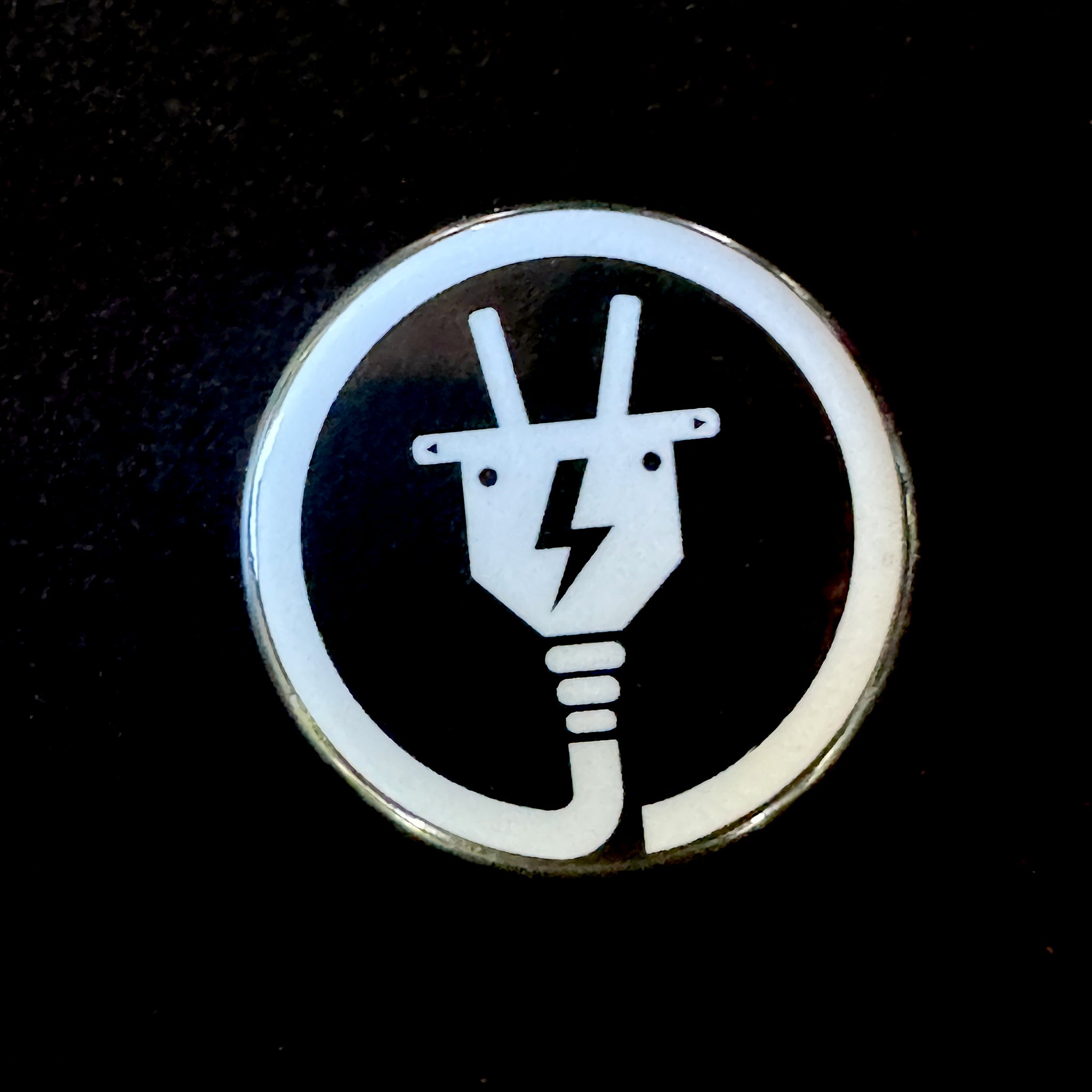 1" button with an electric plug design on a black background